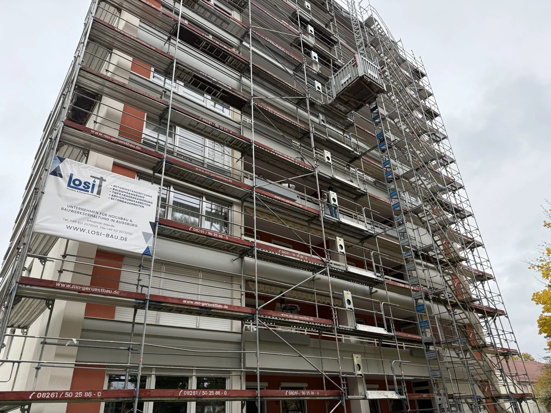 Eingerüstetes Hochhaus während der Fassadensanierung, am Gerüst hängt ein Banner von Losi Bau.