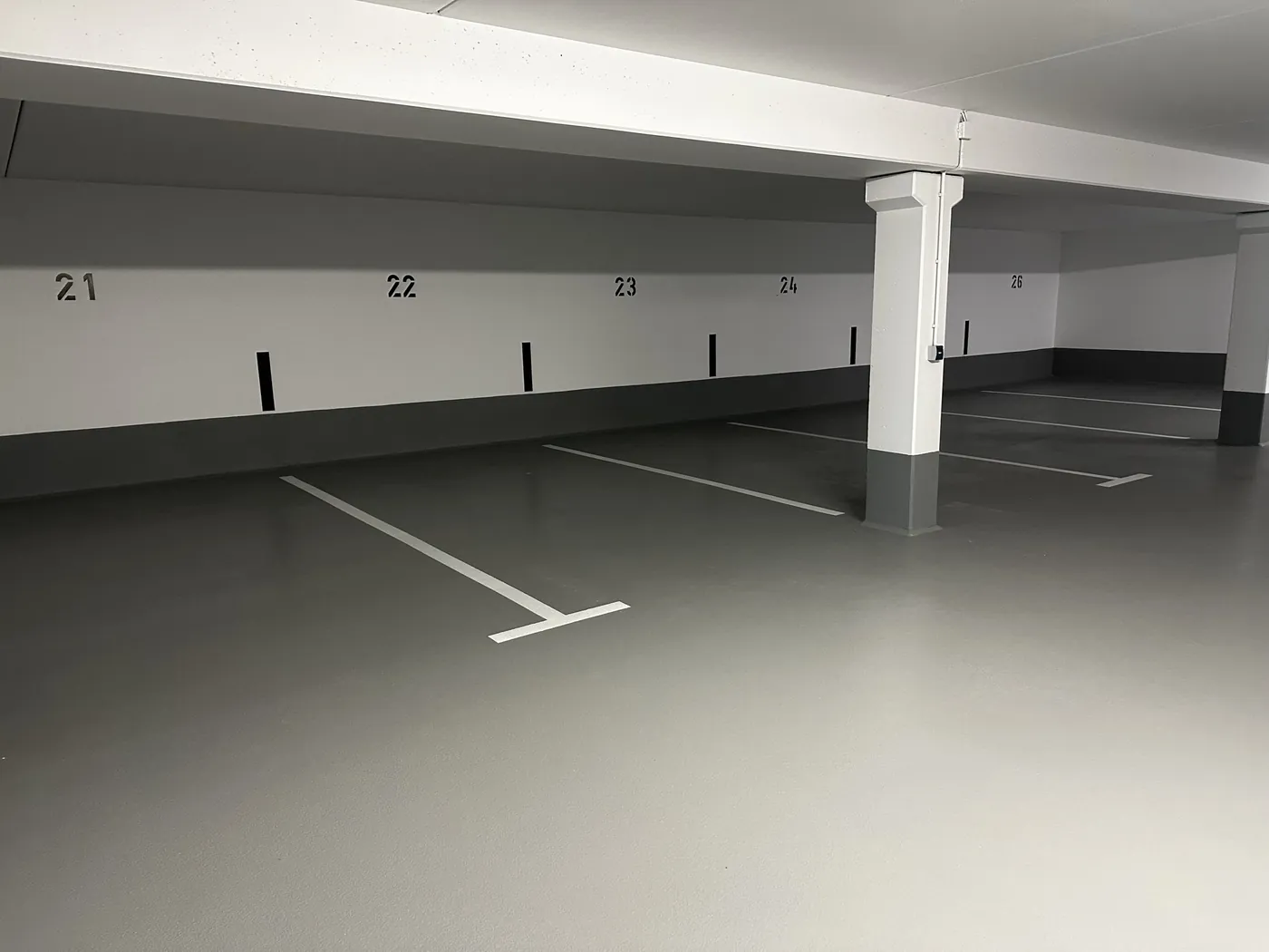 Fertige Tiefgarage mit heller Beschichtung, Stütze und Stellplatznummern.