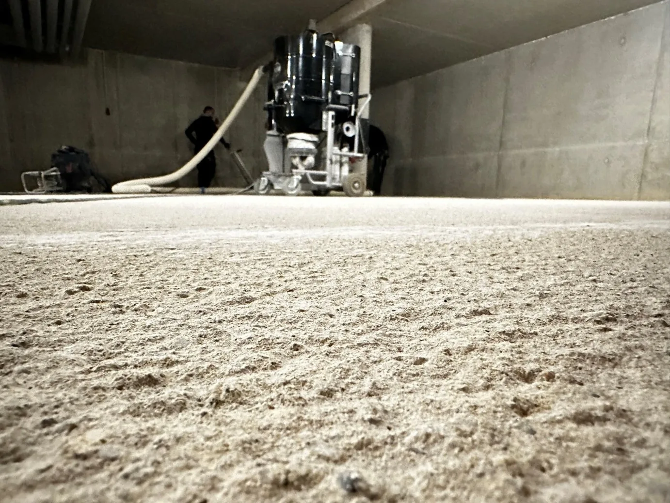 Frisch gestrahlte Betonfläche im Vordergrund, Bodenfräse im Hintergrund